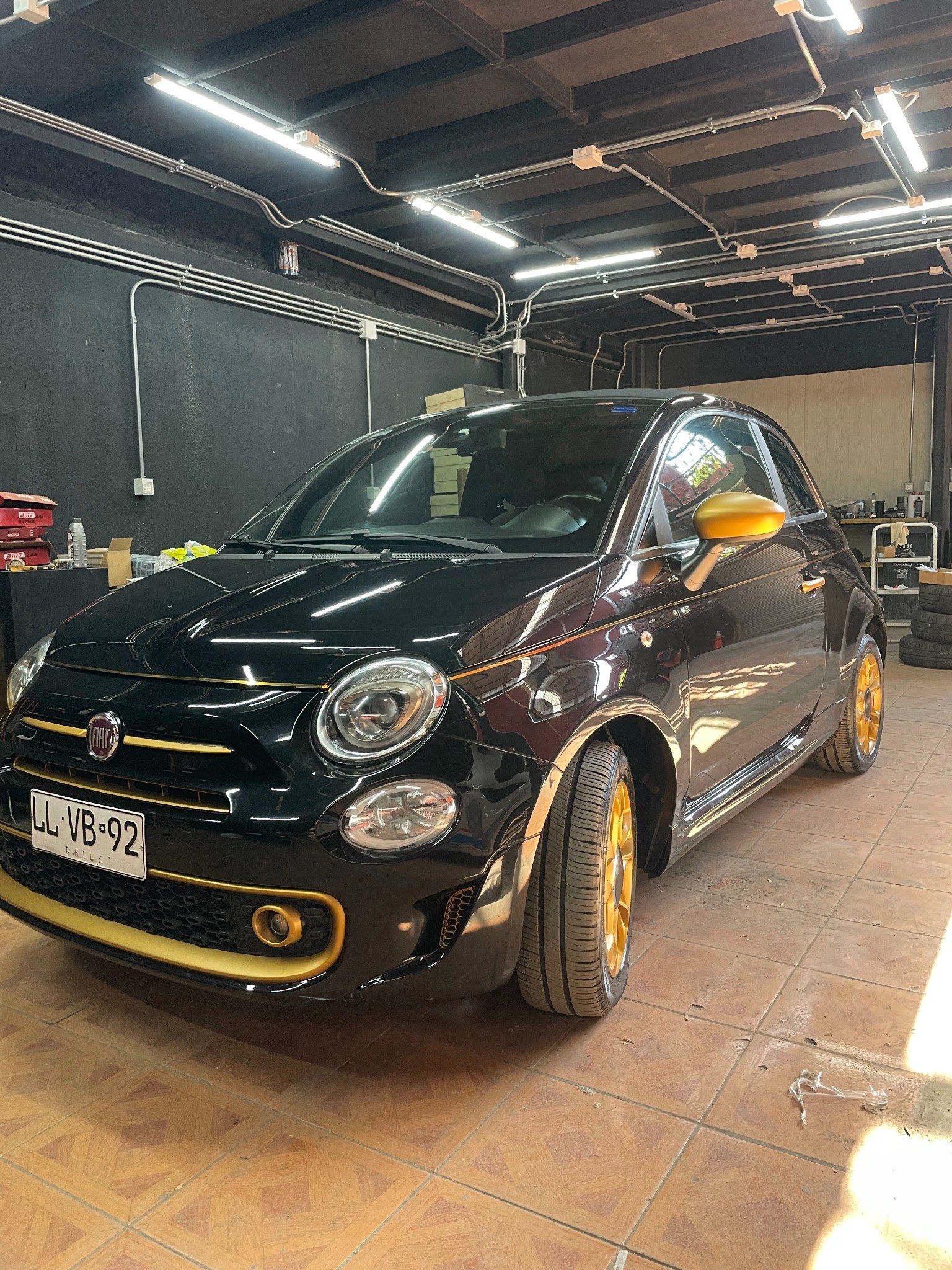 Fiat 500 negro con detalles dorados dentro del taller